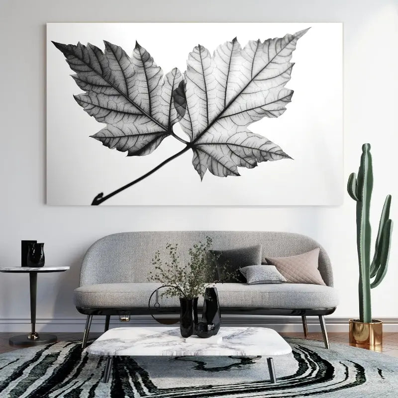 Tableau noir et blanc représentant une feuille d’arbre parmi des végétaux, scène naturelle au style épuré et élégant