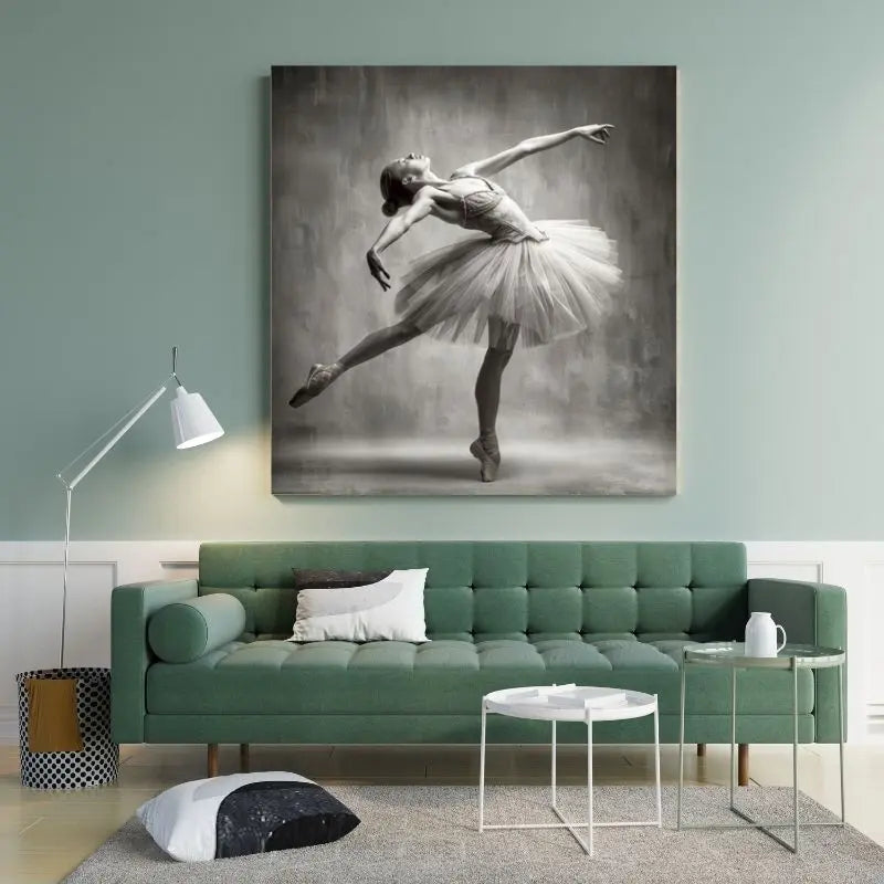 Un canapé vert avec des coussins et une table basse ronde blanche sont disposés devant un mur, complétés par un grand tableau noir et blanc représentant une danseuse de ballet en tutu, évoquant une ambiance art rétro. Le Tableau Danseuse Etoilée Vintage Monochrome au-dessus du canapé ajoute à l'esthétique monochrome vintage.