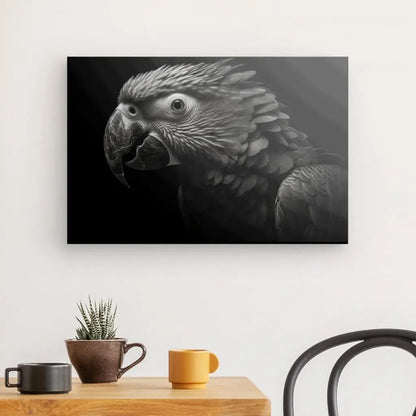 Un Tableau Perroquet Noir et Blanc Ara Portrait Oiseau Parot est accroché à un mur au-dessus d'une petite table en bois avec une plante en pot, une tasse orange et un bol marron. Une chaise noire est adjacente à la table.