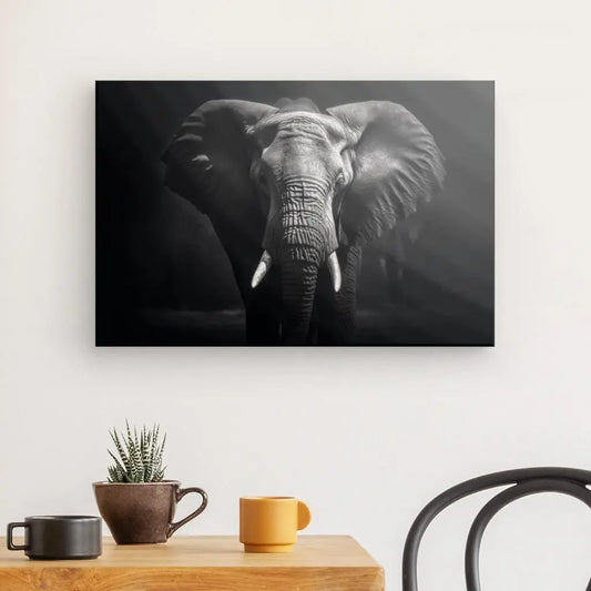 Une photo en noir et blanc, intitulée « Tableau Elephant Savane Portrait Noir et Blanc Sauvage », est accrochée sur un mur blanc au-dessus d'une table en bois avec une plante en pot, une tasse marron et une tasse jaune. Cette élégante pièce de décoration intérieure est complétée par la présence d'une chaise en métal noir partiellement visible.