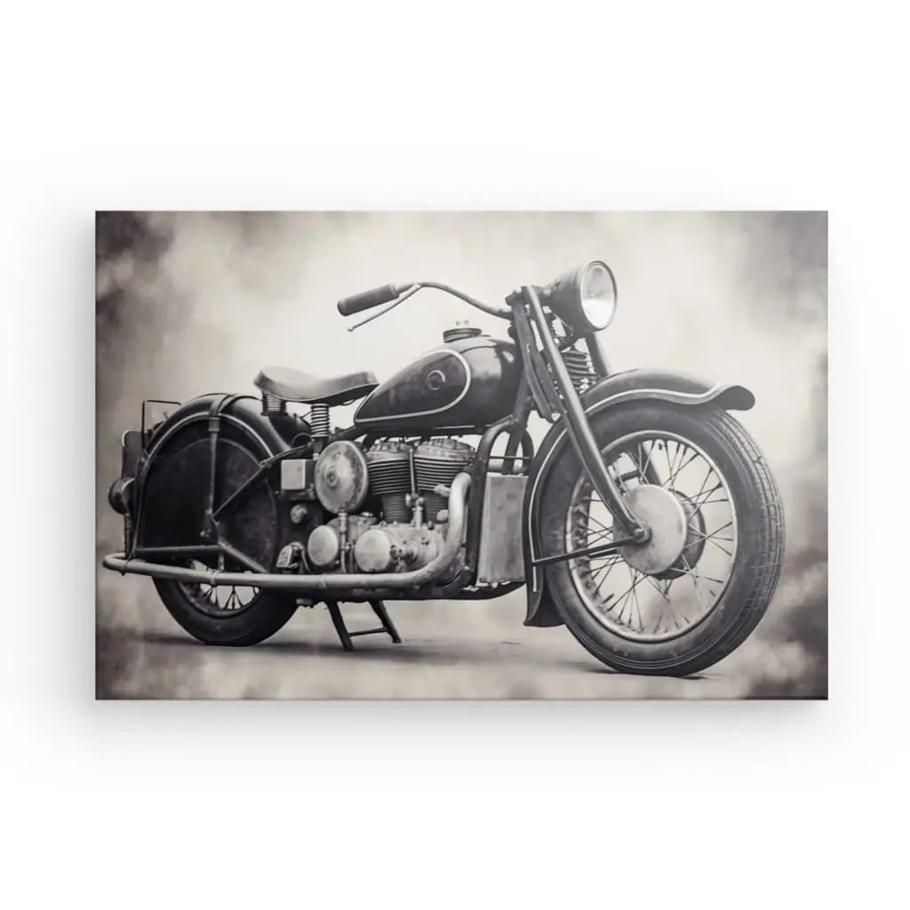 Photographie en noir et blanc d'une Tableau Moto Vintage Moteur Rétro Style Harley Noir et Blanc vintage avec une grande roue avant, des composants de moteur exposés et un seul phare. Le fond est un dégradé de lumière et d’ombres.