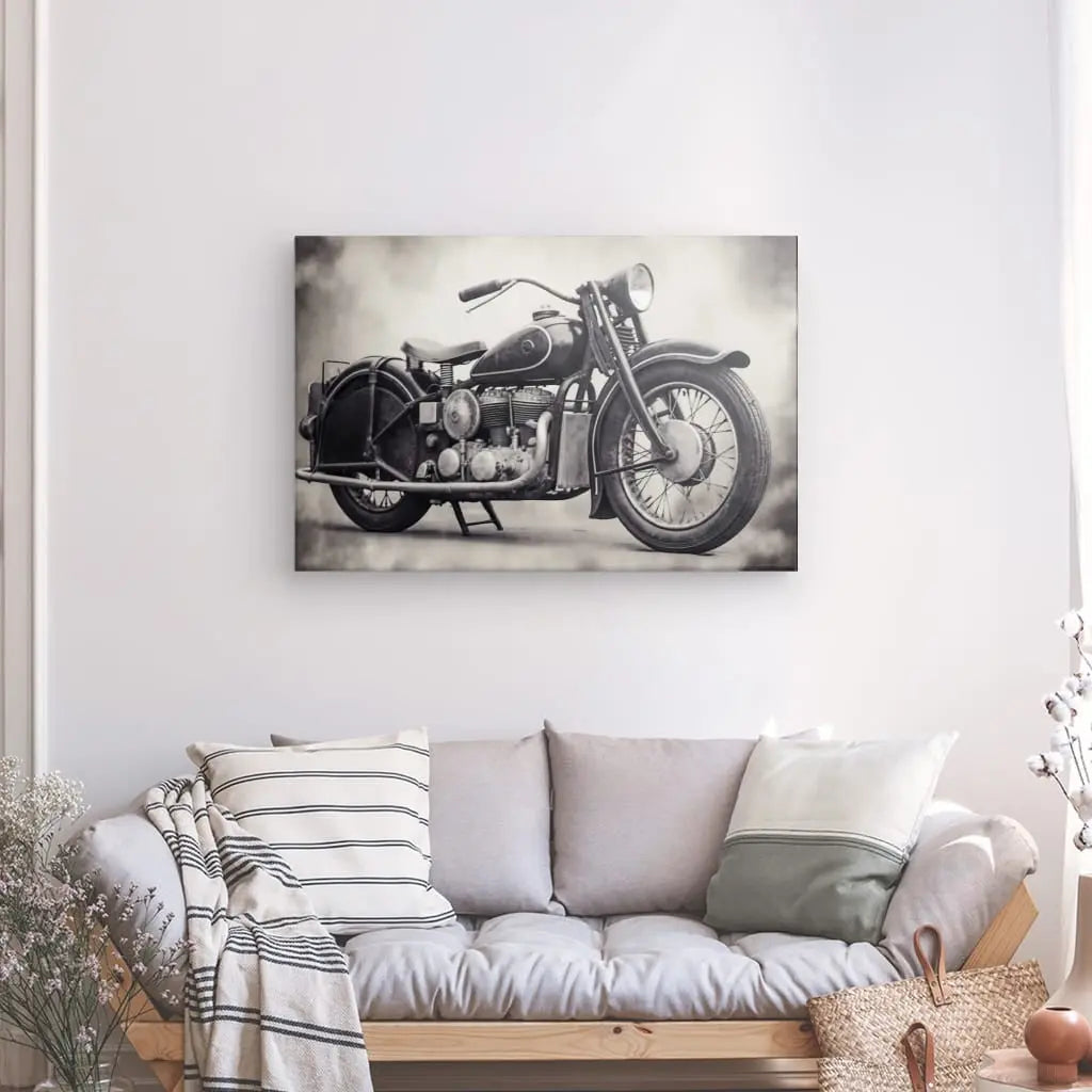 Un Tableau Moto Vintage Moteur Rétro Style Harley Noir et Blanc est accroché sur un mur blanc au-dessus d'un canapé gris avec des oreillers assortis et une couverture. Des plantes décoratives et un panier en osier se trouvent à côté du canapé.