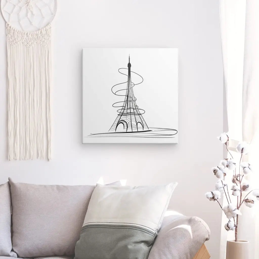 Un salon minimaliste avec un canapé blanc, un oreiller et une décoration murale représentant la Tour Eiffel dans un Tableau Tour Eiffel Abstrait Dessin Traits Moderne Noir et Blanc. Une décoration suspendue en macramé et une petite plante sont également visibles.