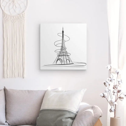 Un salon minimaliste avec un canapé blanc, un oreiller et une décoration murale représentant la Tour Eiffel dans un Tableau Tour Eiffel Abstrait Dessin Traits Moderne Noir et Blanc. Une décoration suspendue en macramé et une petite plante sont également visibles.
