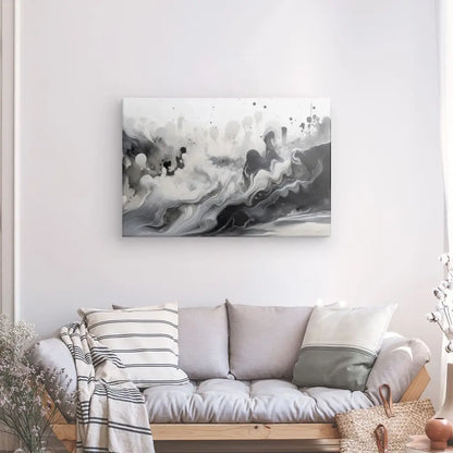 Un canapé gris clair avec des coussins rayés et unis est placé contre un mur blanc présentant un Tableau Abstrait Nuances de Gris Design Noir et Blanc. Un petit panier et un décor végétal sont positionnés à côté du canapé, créant un design sophistiqué en nuances de gris.