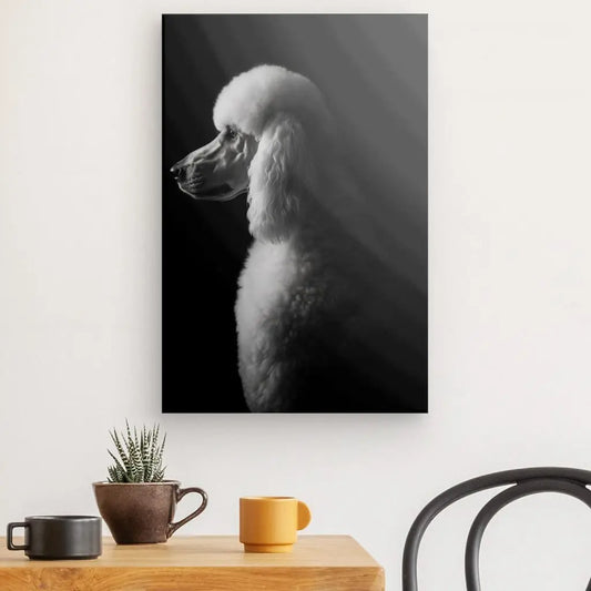 Un portrait en noir et blanc d'un caniche, respirant l'élégance canine, est accroché au mur au-dessus d'une table en bois avec une plante en pot, une tasse noire et une tasse jaune. Une chaise noire est partiellement visible à droite dans cet exquis Tableau Caniche Royal Portrait Canin Chien Noir et Blanc.