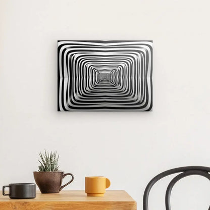 Un tableau Hypnotique Spirale Noir et Blanc Art Abstrait Minimaliste, un véritable art abstrait minimaliste, est suspendu sur un mur blanc au-dessus d'une table en bois avec une petite plante et trois mugs. Une chaise noire est partiellement visible à droite.