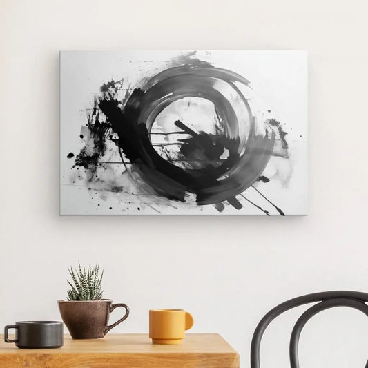 Une peinture abstraite monochromatique dans le style de l'expressionnisme abstrait, avec des coups de pinceau circulaires noirs sur fond blanc, est suspendue au-dessus d'une table en bois avec une plante et deux tasses, une marron et une jaune. Une chaise noire se trouve à proximité, créant un fascinant Tableau Moderne Gris Noir Blanc Abstrait Tâches.