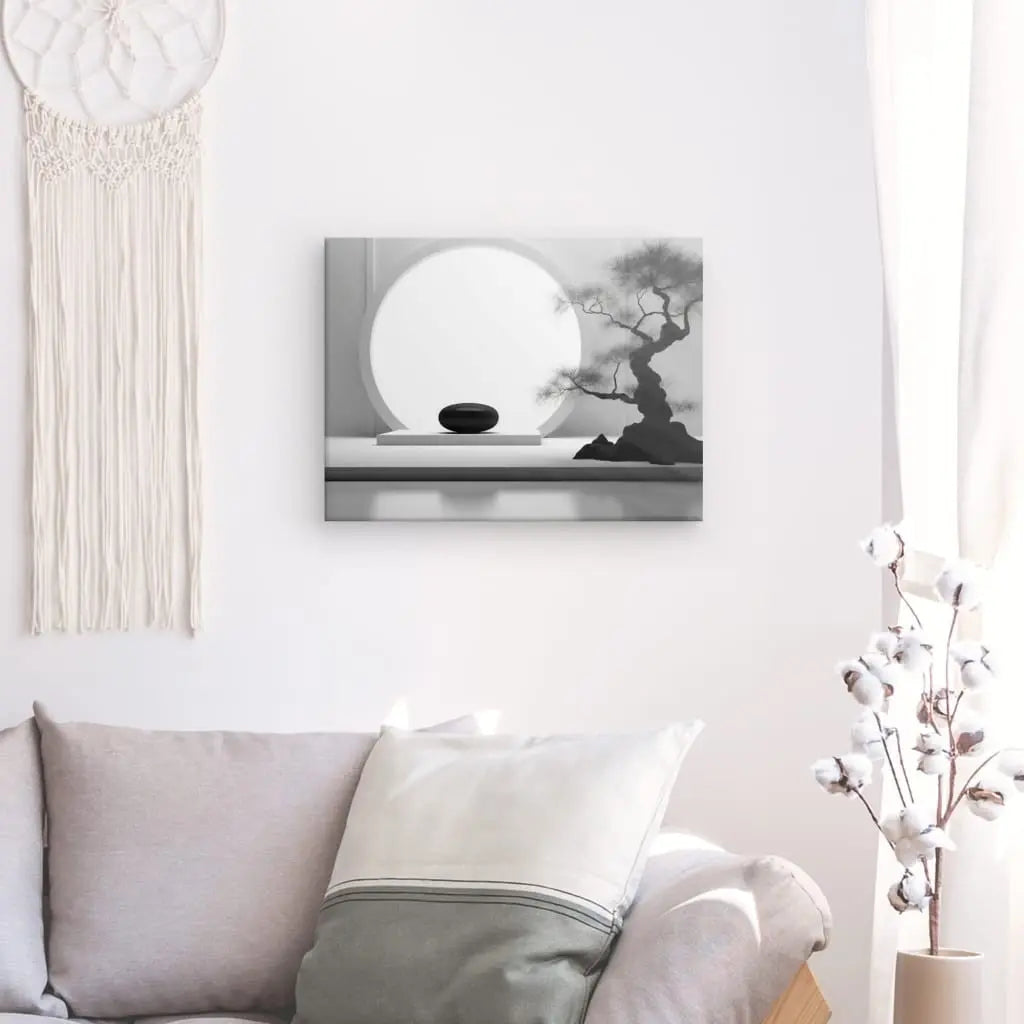 Salon minimaliste avec un canapé gris, un oreiller blanc, une décoration murale et un Tableau Bonsai Relaxation Zen Noir et Blanc encadré au mur, incarnant le zen de relaxation bonsaï. Une tige de cotonnier dans un vase à côté du canapé ajoute à la sérénité et à l'équilibre.