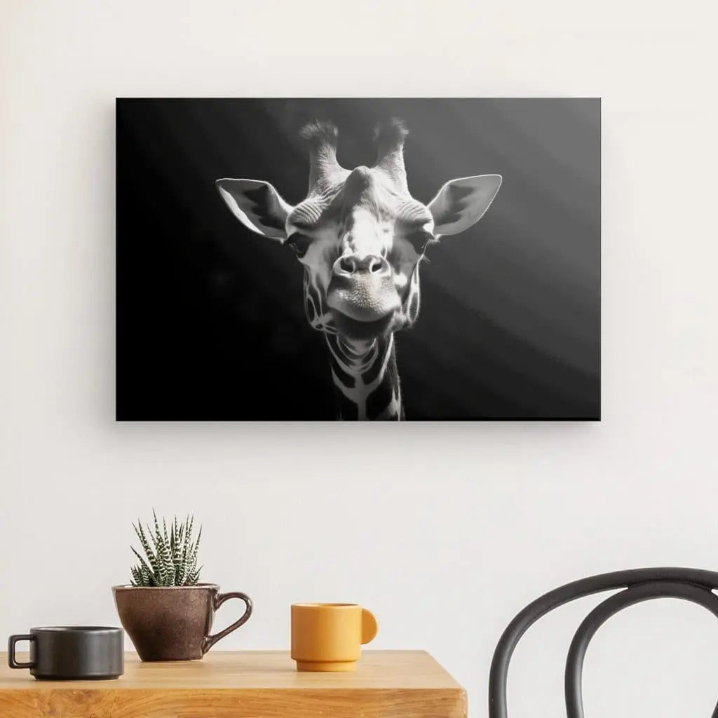 Tableau Portrait Girafe Drôle Gros Plan Noir et Blanc sur un mur au-dessus d'une table en bois avec une plante en pot, une tasse marron et une tasse jaune.