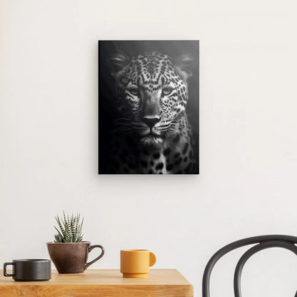 Une photographie en noir et blanc Tableau Panthère Portrait Sauvage Noir et Blanc d'un léopard est accrochée sur un mur blanc au-dessus d'une table en bois avec deux tasses, une petite plante dans un pot et une chaise noire à proximité.