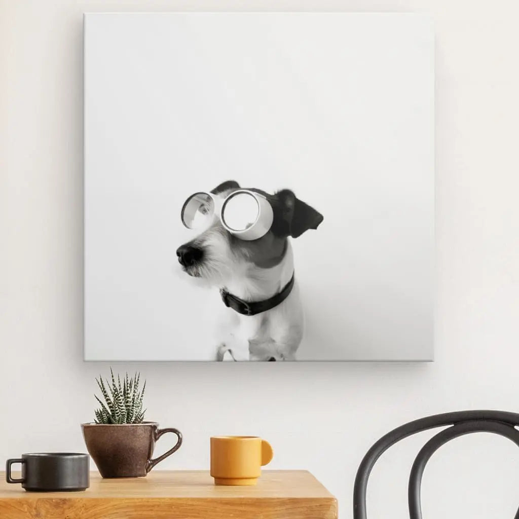 Une reproduction photo Tableau Chien Drôle Lunettes Aviateur Noir et Blanc d'un chien portant des lunettes rondes, exposée au-dessus d'une table en bois avec une chaise en métal, une tasse et une petite plante en pot.