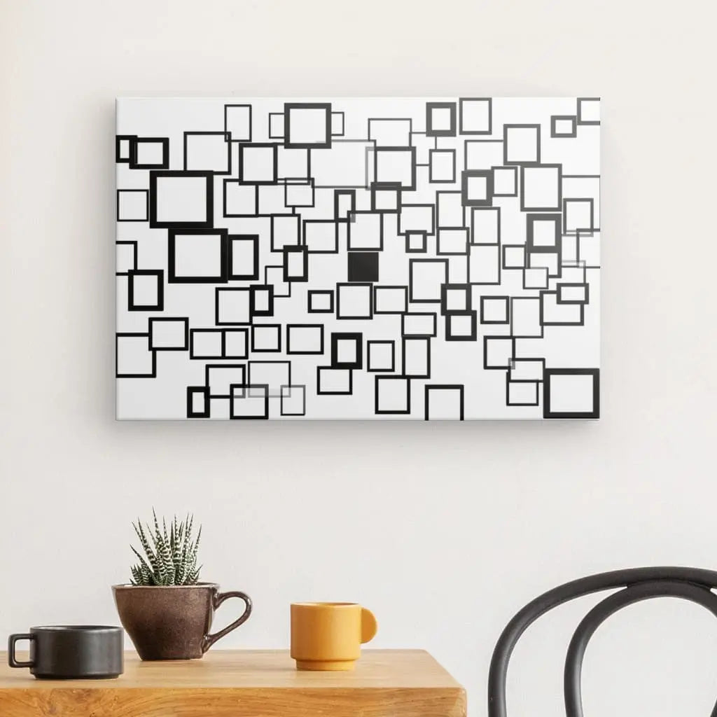 Tableau géométrique abstrait noir et blanc Carrés Rectangles Formes Art Abstrait Impressions sur toile monochromes sur un mur au-dessus d'une table en bois avec une plante et une tasse jaune.
