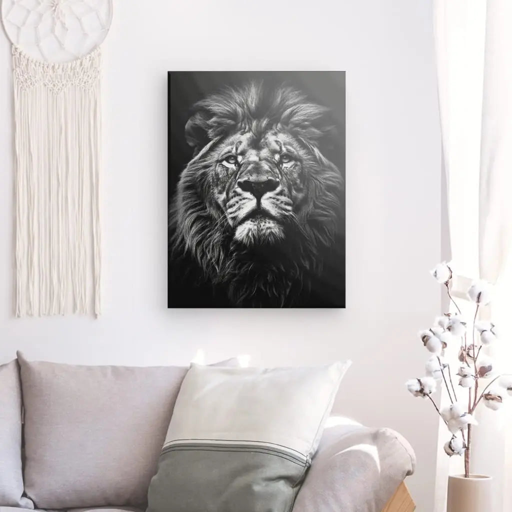 Une impression Tableau Lion Gros Plan Noir et Blanc sur toile, accrochée au mur d'un salon au-dessus d'un canapé gris, accompagnée de décorations minimalistes.