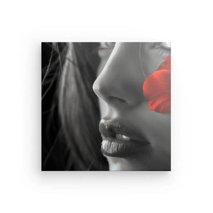 Gros plan d'un visage de femme avec un pétale de fleur rouge couvrant un œil, monochrome avec couleur sélective, imprimé sur toile Tableau Portrait Femme Noir et Blanc Fleur Rouge.