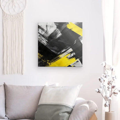 Un salon avec un canapé gris clair, un grand coussin blanc, un cotonnier dans un vase et une tenture murale en macramé est complété par un exquis Tableau Noir Blanc Jaune Art Peinture Abstraite au mur. Cette décoration contemporaine sophistiquée crée une ambiance invitante et élégante.