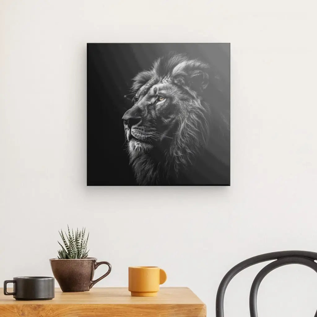 Un mur présente de profil un Tableau Lion Roi Jungle Noir et Blanc Yeux Marrons. Ci-dessous, une table en bois contient une succulente en pot, une tasse marron et une tasse jaune. Une chaise noire est partiellement visible à droite, nouant cette élégante décoration d'intérieur.