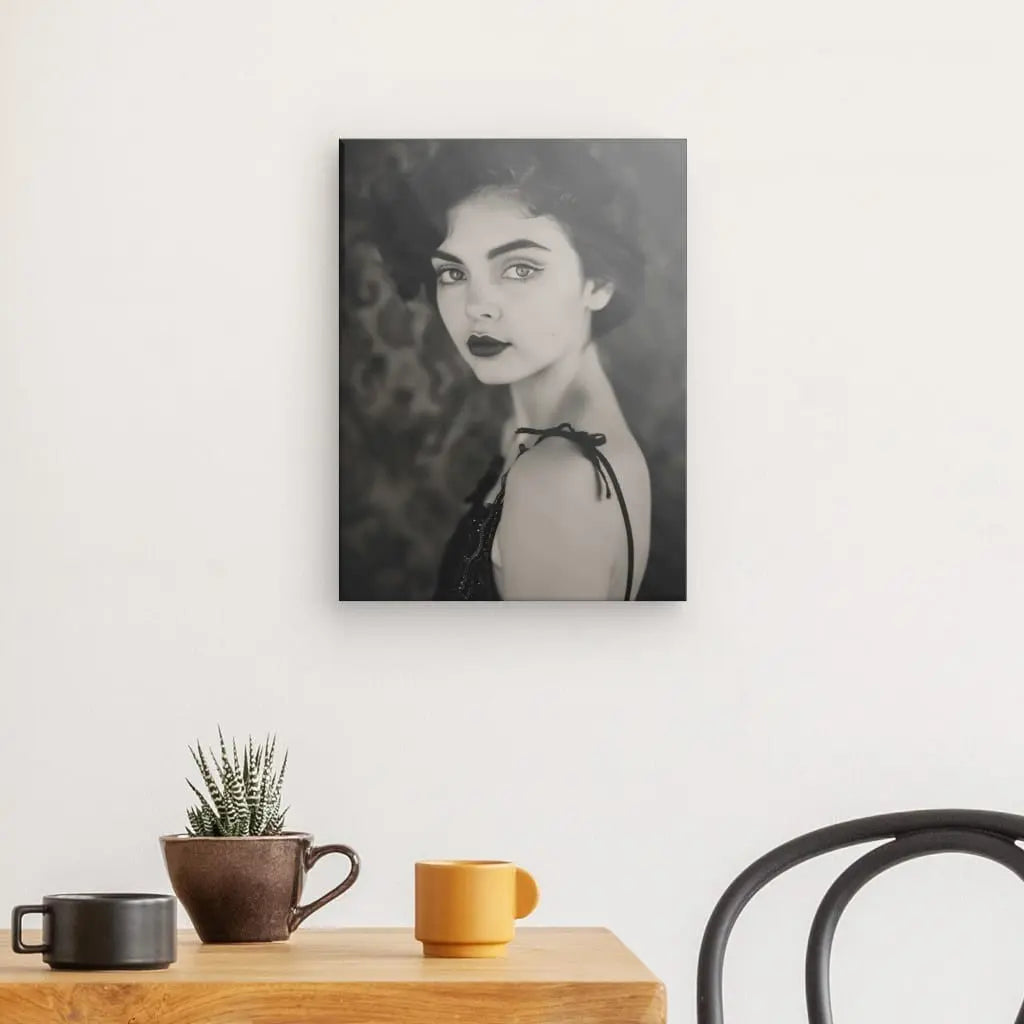 Un Tableau Femme Vintage Portrait Noir et Blanc orne le mur, présentant un portrait en noir et blanc d'une femme au-dessus d'une table en bois avec une plante en pot, une tasse marron et une tasse jaune. À droite, une chaise noire est partiellement visible, ajoutant à l'élégance intemporelle de la scène.