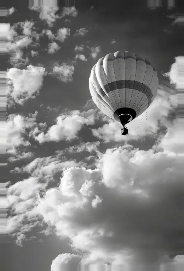 Un Tableau Montgolfière Ballon Noir et Blanc flotte dans le ciel parmi les nuages épars dans une photographie saisissante, parfaite pour ajouter une touche d'élégance vintage à toute œuvre d'art intérieure.