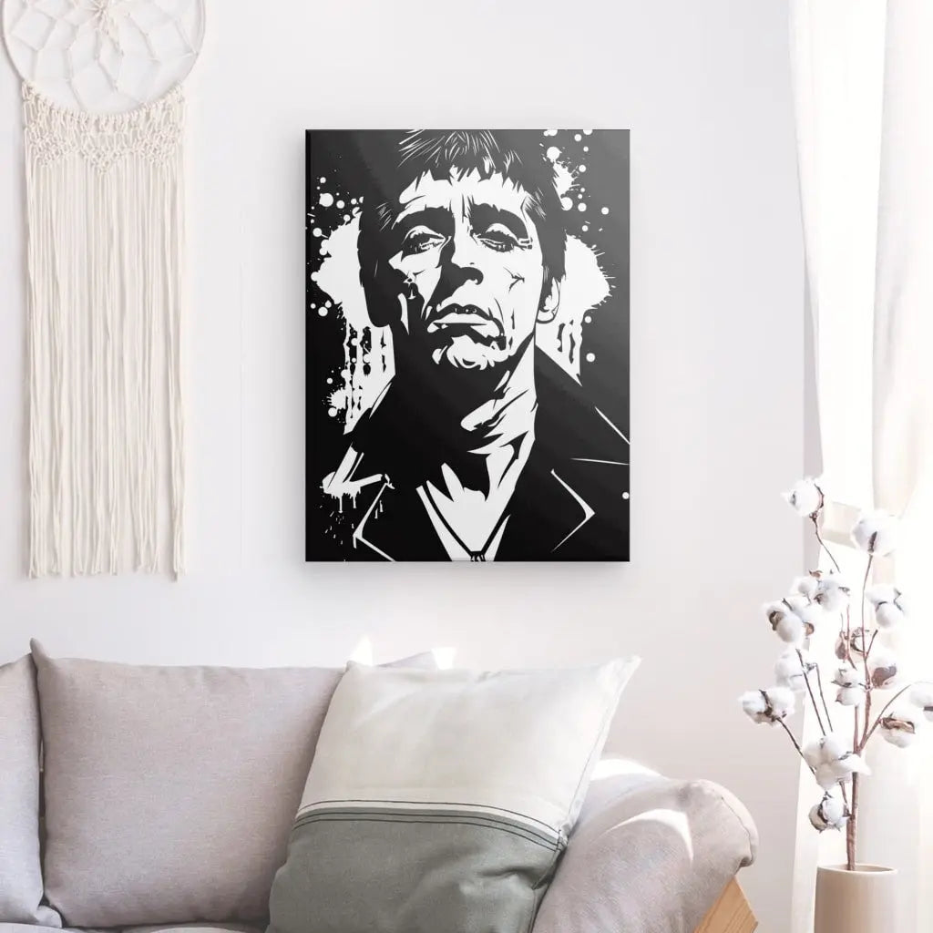 Un portrait graphique en noir et blanc d'un homme à l'air sérieux, qui rappelle Al Pacino dans le rôle de Tableau Scarface Tony Montana Dessin Noir et Blanc, est accroché sur un mur blanc au-dessus d'un canapé beige avec des oreillers. Des branches de coton et une pièce en macramé décorent l'espace.