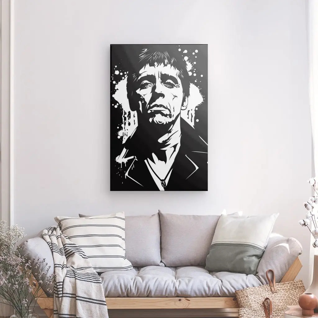 Un portrait en noir et blanc de *Tableau Scarface Tony Montana Dessin Noir et Blanc* est suspendu au-dessus d'un canapé gris clair avec des oreillers rayés et unis dans un salon minimaliste et bien éclairé.