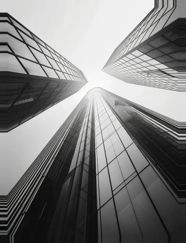 Une photographie en noir et blanc de quatre grands gratte-ciels noir et blanc avec des extérieurs en verre, prise en contre-plongée vers le haut, convergeant vers le centre de l'image. Ce Tableau Buildings Tours Noir et Blanc constitue une superbe décoration murale moderne.