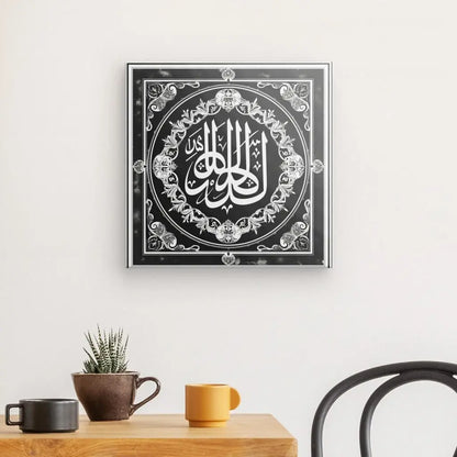 Une œuvre d'art calligraphique islamique encadrée, Tableau Symbole Allah Dieu Noir et Blanc, est accrochée à un mur blanc au-dessus d'une table en bois avec une petite plante et deux tasses, ajoutant une touche d'élégance et de décoration intérieure à l'espace.