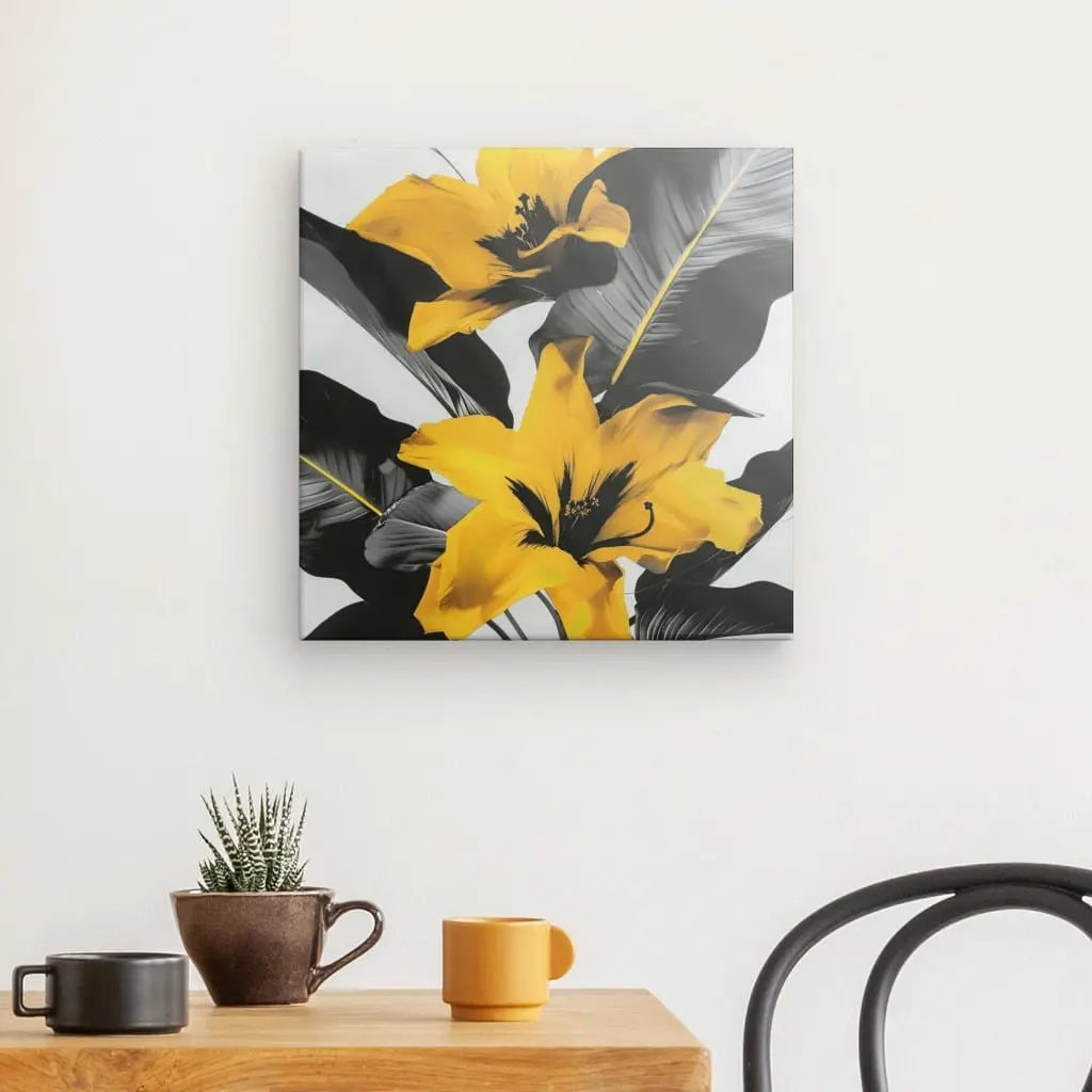 Un Tableau Fleurs Jaunes Design Noir et Blanc est suspendu au-dessus d'une table en bois avec un petit cactus et deux tasses, une marron et une jaune. Une chaise en métal noir est partiellement visible.