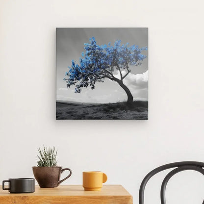 Un mur présente une peinture Tableau Campagne Monochrome Arbre Feuilles Bleues. En dessous, une petite table en bois contient deux tasses et une plante en pot. Une chaise noire est partiellement visible.