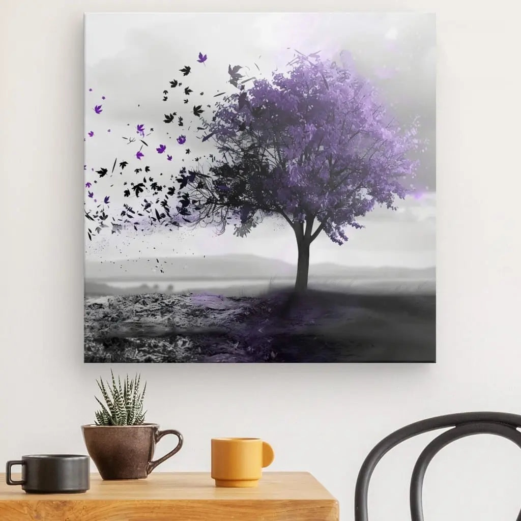 Le Tableau Arbre Violet Paysage Noir et Blanc présente un arbre aux feuilles violettes sur un paysage brumeux. Des oiseaux noirs volent de l'arbre. En contrebas, une petite table avec deux plantes succulentes en pot et deux tasses côtoie une chaise noire, complétant la décoration intérieure de ce enchanteur paysage noir et blanc.