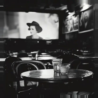 Tables de café vides avec deux verres sur l'un d'eux. Un film classique en noir et blanc, un véritable Tableau Cinéma Classique Scène Noir et Blanc, avec un acteur au chapeau, joue sur un écran de projection en arrière-plan.