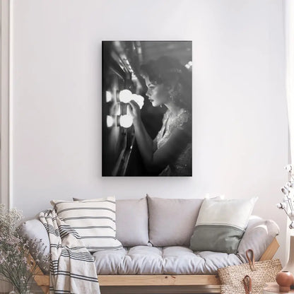 Un Tableau Pin up Femme Rétro Noir et Blanc représentant une femme regardant dans un miroir de courtoisie éclairé est suspendu au-dessus d'un canapé de couleur claire avec des coussins rayés dans un salon bien éclairé, ajoutant une touche de décoration vintage.
