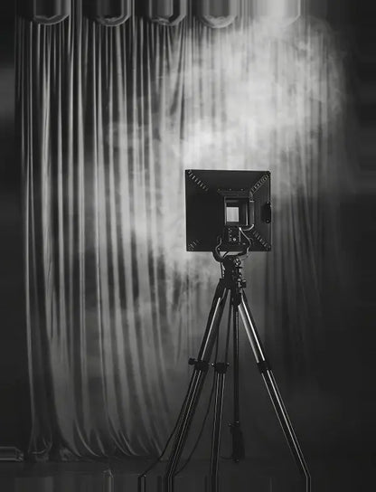 Une caméra sur trépied se tient devant un rideau fermé avec des effets de lumière et de fumée spectaculaires, évoquant l'atmosphère d'un Tableau Projecteur Cinéma Noir et Blanc.