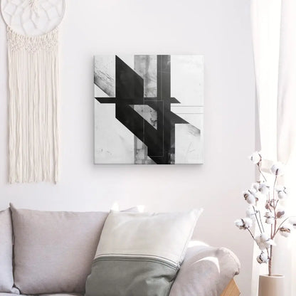 Un Tableau Dessin Abstrait Géométrique Noir et Blanc est accroché sur un mur blanc au-dessus d'un canapé gris clair avec un oreiller blanc. Une tenture murale en macramé se trouve à gauche et des branches de coton blanc dans un vase sont à droite.