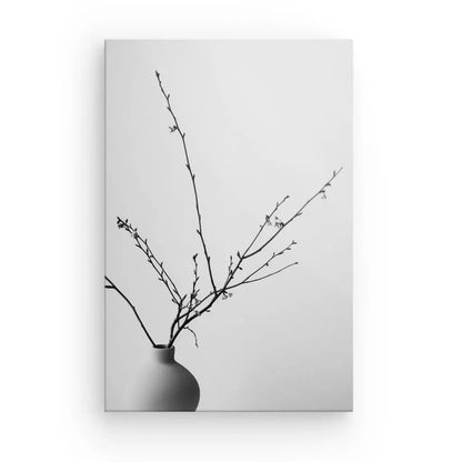 Image en noir et blanc d'un vase simple avec des branches nues qui s'en étendent, placé sur un fond uni de couleur claire, incarnant un art élégant. Tableau Nature Morte Pot Plante Branches Noir et Blanc.