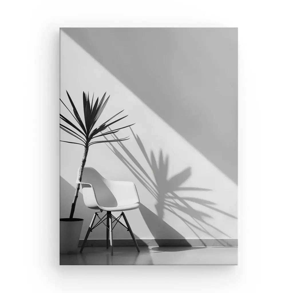 Une chaise blanche se trouve à côté d’une plante en pot, projetant Tableau Intérieur Moderne Jeux de Lumières Monochromes sur un mur dans une pièce minimaliste et ensoleillée, créant un tableau intérieur moderne exquis.