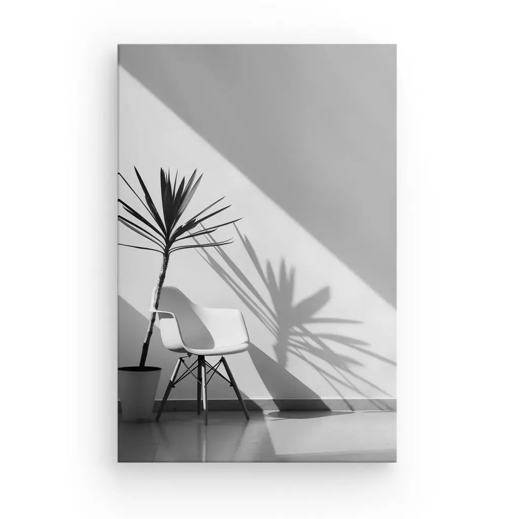 Une chaise blanche à côté d'une plante en pot projetant Tableau Intérieur Moderne Jeux de Lumières Monochromes sur un mur dans une pièce minimaliste et bien éclairée.