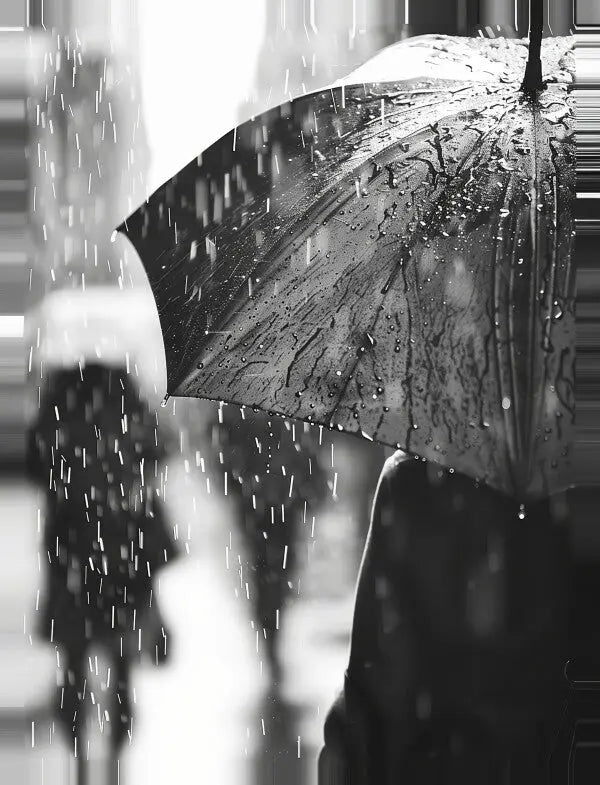 Image en noir et blanc d’une personne tenant un parapluie sous la pluie. Des gouttelettes sont visibles sur le parapluie, avec des figures floues en arrière-plan ; une œuvre d'art évocatrice capturant une scène pluvieuse, *Tableau Pluie Noir et Blanc*.