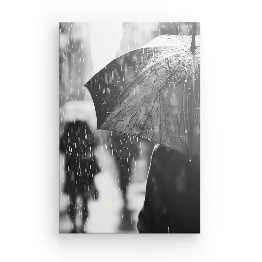 Image en noir et blanc de personnes marchant sous la pluie avec des parapluies. Le parapluie le plus proche est bien visible, couvert de gouttes de pluie. Des personnages flous sont en arrière-plan, créant une scène pluvieuse qui ressemble à un Tableau Pluie Noir et Blanc.