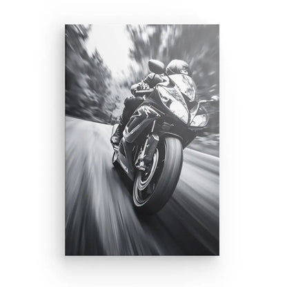 Une photo Tableau Moto Sport Vitesse Noir et Blanc capture un motocycliste sur une moto de sport, roulant à toute vitesse sur une route sinueuse avec un arrière-plan flou qui met l'accent sur le mouvement.