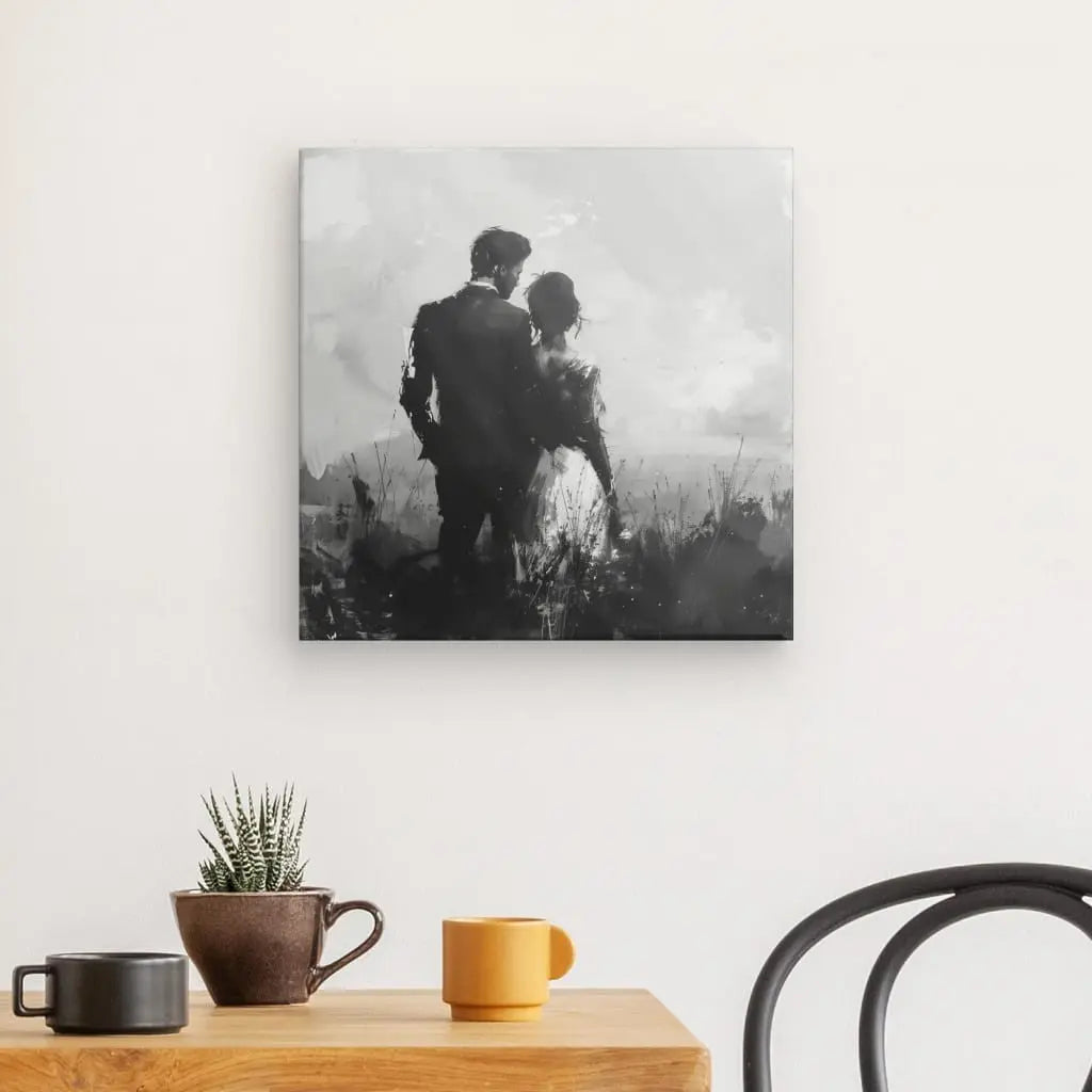 Peinture en noir et blanc d'un couple vu de dos, montée sur un mur blanc au-dessus d'une table en bois avec deux tasses à café, une succulente et une chaise noire. Ce Tableau Couple Nature Peinture Noir et Blanc apporte une touche élégante à n'importe quelle pièce.