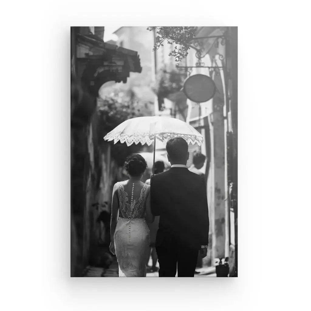 Un couple habillé formellement marche dans une ruelle étroite, la femme tenant un parasol lacé au-dessus de leur tête. Le Tableau Mariés Photo de Dos Ombrelle Noir et Blanc capture une sensation d'art romantique, soulignant l'élégance intemporelle de leur voyage ensemble.