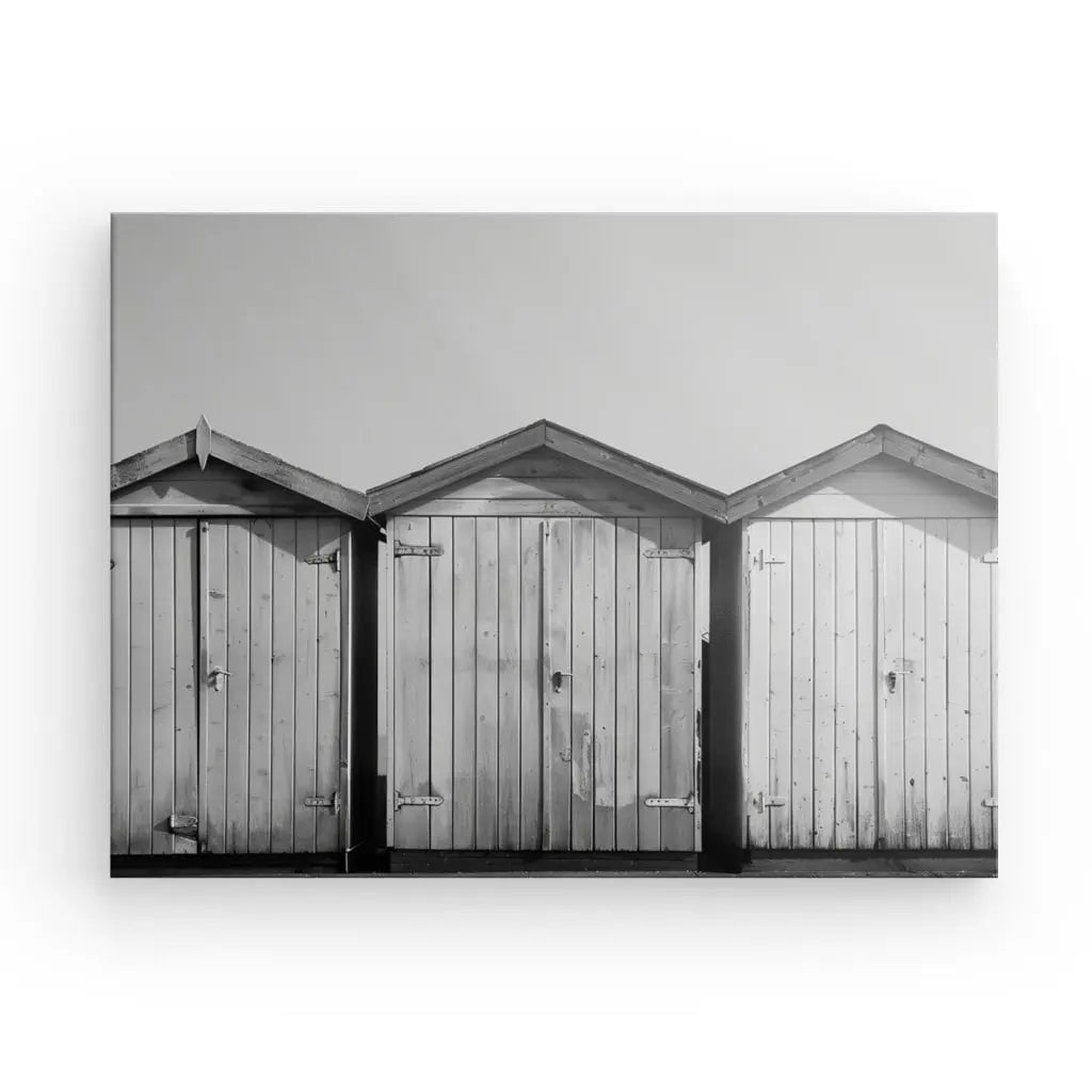 Photographie en noir et blanc de trois cabanes de plage en bois adjacentes, aux toits pointus, aux volets fermés et aux charnières apparentes, parfaites pour une décoration artistique côtière, sur fond de ciel dégagé.

devient:

Tableau Cabanons Plage Sable Noir et Blanc de trois cabanes de plage en bois adjacentes avec des toits pointus, des volets fermés et des charnières visibles, parfaits pour une décoration côtière, sur fond de ciel dégagé.