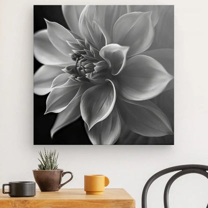 Une photographie en niveaux de gris intitulée "Fleur Lotus Gros Plan Noir et Blanc" est exposée sur un mur au-dessus d'une table en bois ornée d'une plante en pot et de deux tasses à café, créant un élégant tableau noir et blanc. Une chaise noire est partiellement visible sur la droite, renforçant encore la décoration zen.