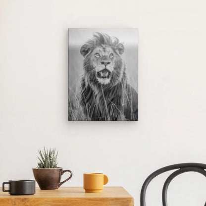 Photo en noir et blanc d'un lion accroché sur un mur blanc, au-dessus d'une table en bois avec une petite plante en pot, une tasse marron et une tasse orange. Une chaise noire est partiellement visible à droite, créant une élégante décoration animale avec le Tableau Lion Rugissement Noir et Blanc.