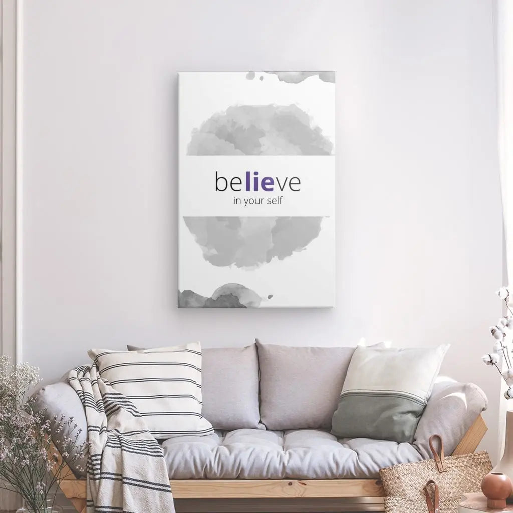 Un tableau "Believe" Noir Blanc et Violet avec le texte "croyez en vous-même" est suspendu au-dessus d'un canapé de couleur claire avec des oreillers rayés et unis dans un salon minimaliste, mettant en valeur une typographie élégante et des encres de haute qualité.