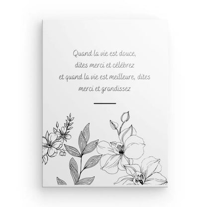 Pièce de décoration intérieure raffinée, le « Tableau Citation Fleurs et Gratitude Inversé » présente une carte blanche avec des illustrations florales noires et un texte en français au centre qui dit : « Quand la vie est douce, dites merci et célèbrez et quand la vie est meilleure. , dites merci et grandissez.