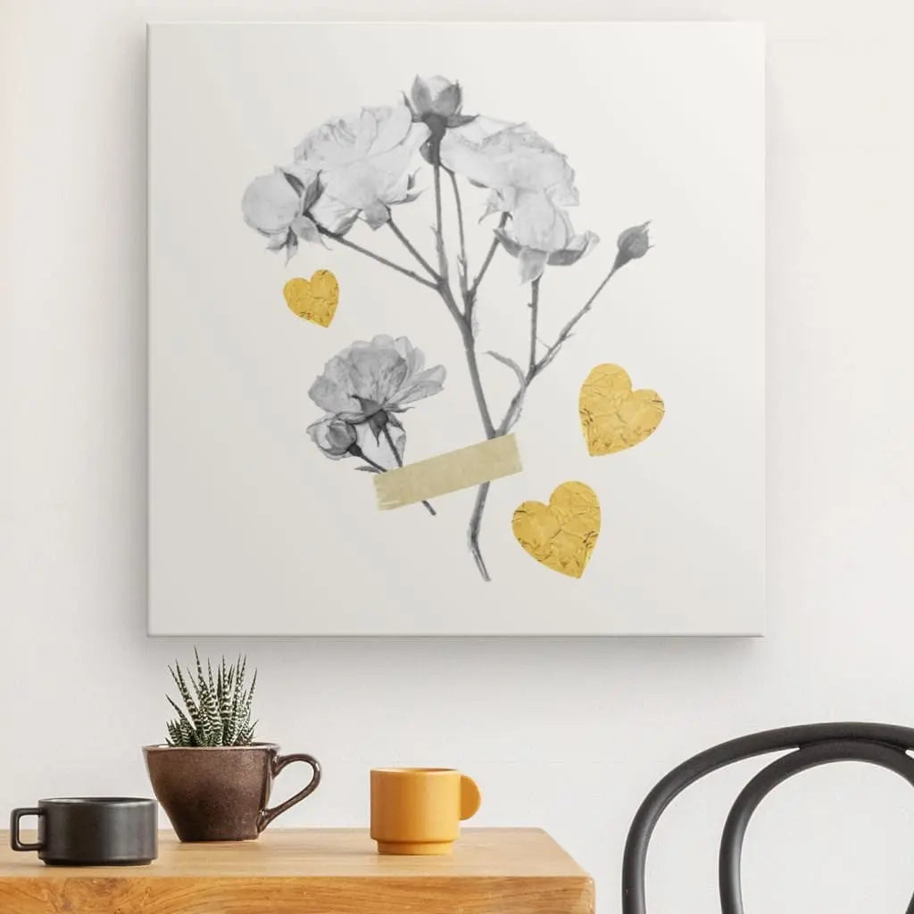 Le Tableau Fleurs Séchées Monochrome Coeurs Jaunes, témoignage de la décoration intérieure, est exposé au-dessus d'une table en bois avec un cactus en pot, une tasse noire et une tasse jaune. Une partie d'une chaise noire est visible à droite.