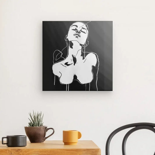 Un Tableau Dessin Femme Noir et Blanc Art Moderne est élégamment exposé sur un mur au-dessus d'une table en bois ornée d'une petite plante en pot et de deux tasses, à côté d'une chaise noire, incarnant une décoration intérieure élégante.