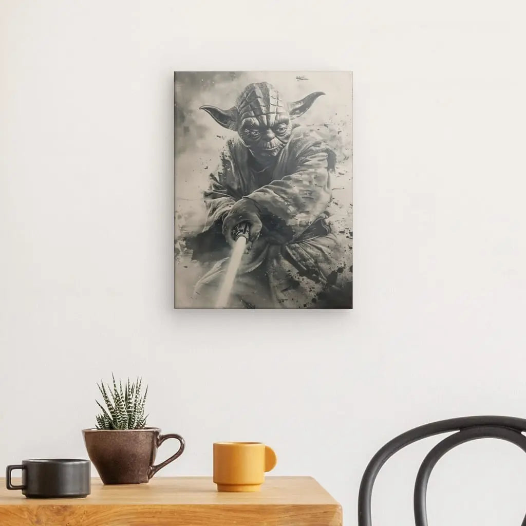 Une pièce avec une petite table contenant une tasse marron et une tasse jaune, une plante en pot et une chaise ; sur le mur au-dessus de la table se trouve un Tableau Yoda Star Wars Noir et Blanc, ajoutant une touche de charme à la décoration intérieure.